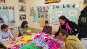 A group sat around a table with lots of coloured fabrics on the table